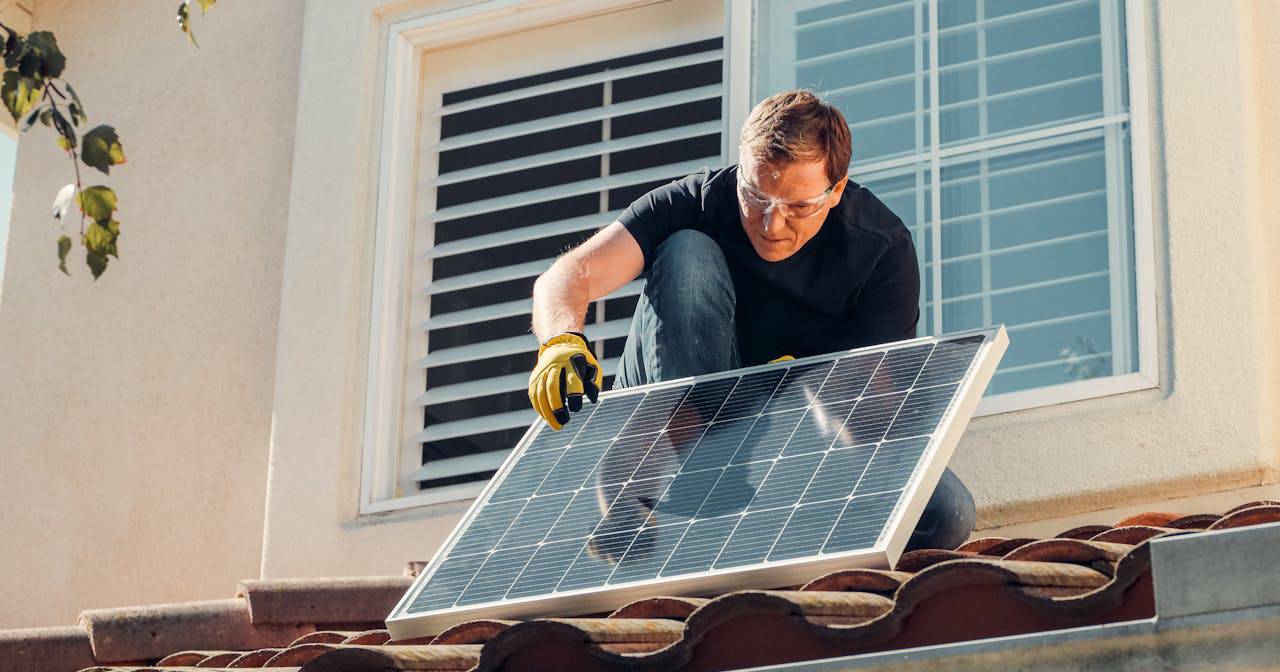 Man with gloves holding polycrystalline solar panels on the roof