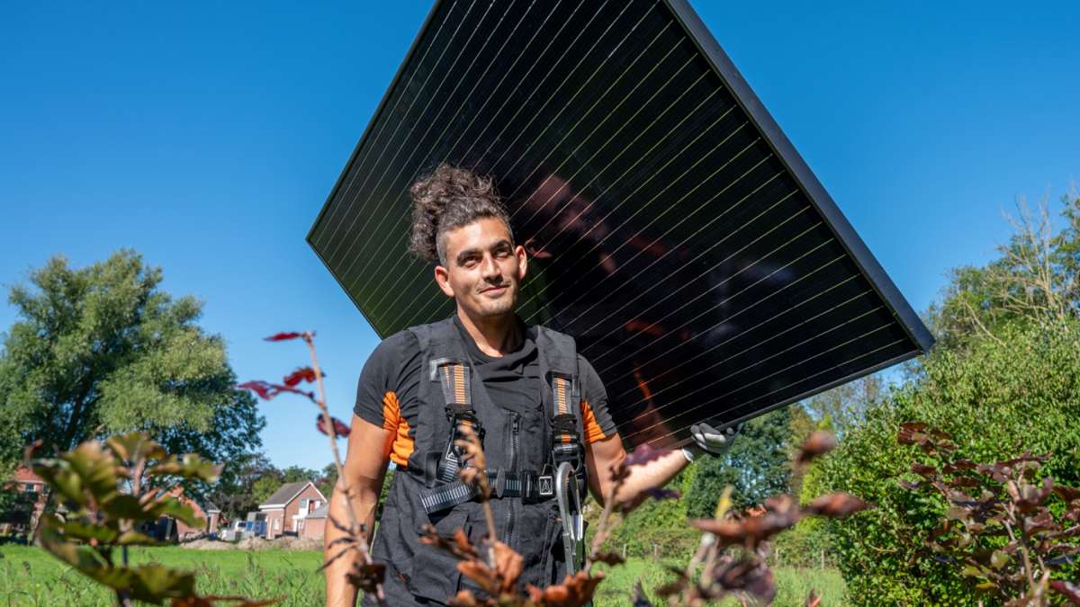 A technician holding a large solar panel